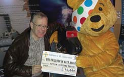 THE HYDE FUNDRAISERS - John Leeson presents BBC'S CHILDREN IN NEED mascot, Pudsey, with a 15,000 cheque.
